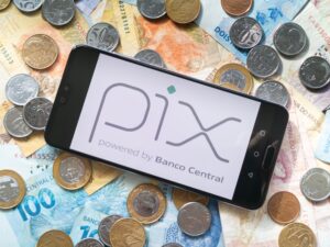 Celular com logo do PIX sobre cédulas e moedas de real brasileiro