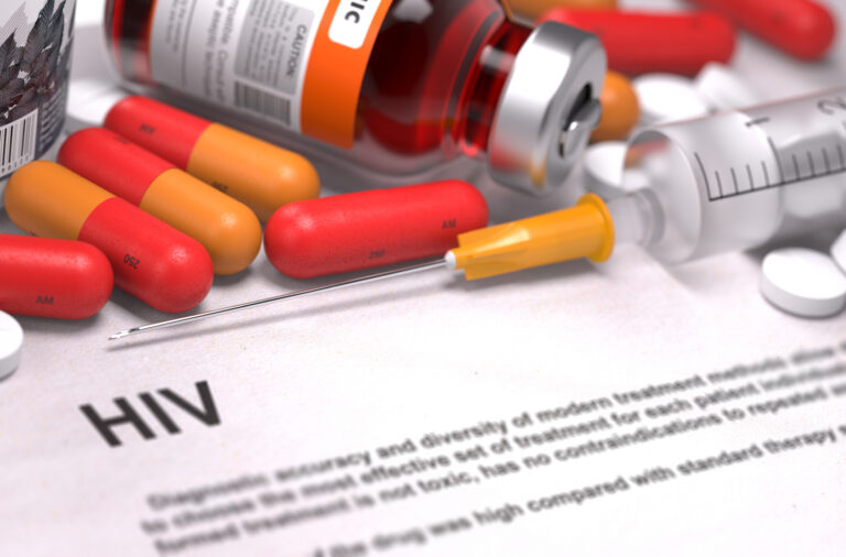 Seringa, cápsulas e frasco de medicamento sobre documento com a palavra HIV em destaque