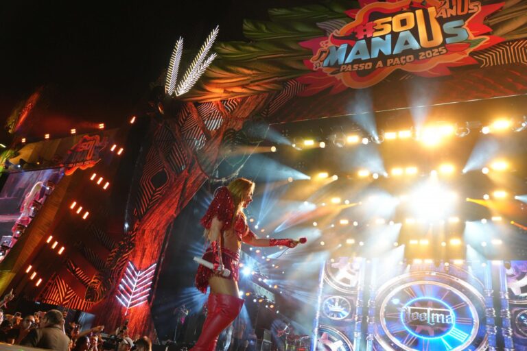 Joelma segura uma rosa vermelha durante seu show no palco principal do #SouManaus Passo a Paço 2025, em Manaus, sob iluminação intensa e com o telão exibindo seu nome.