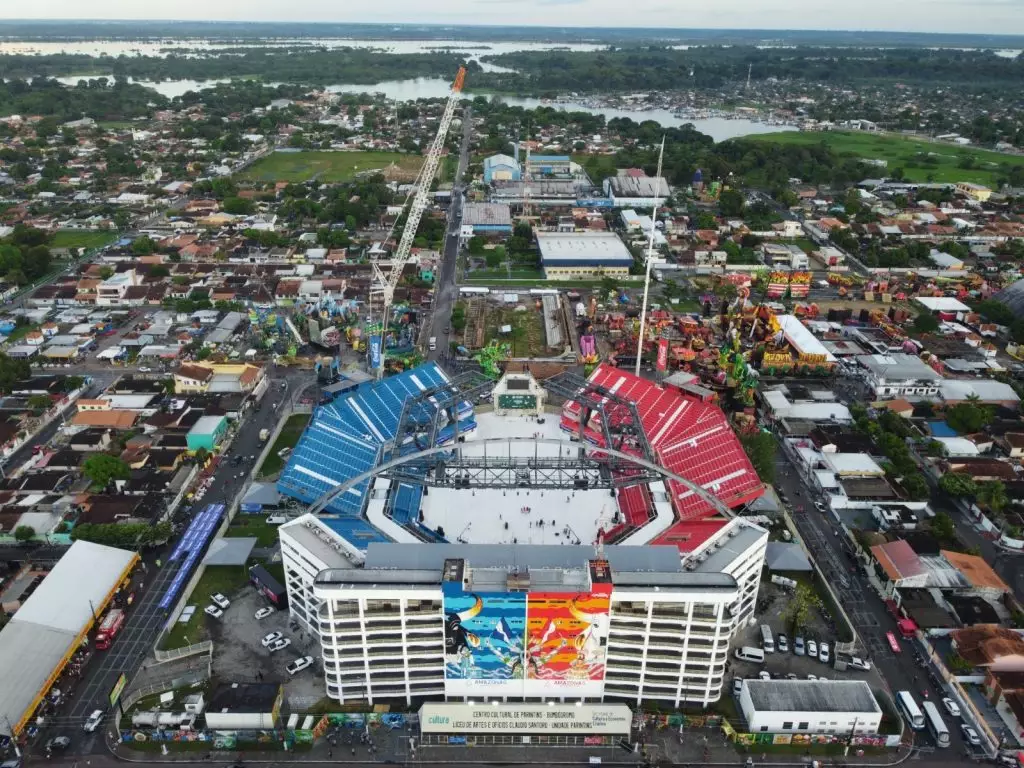 Imagem aérea mostra o Bumbódromo de Parintins com as arquibancadas azul e vermelha, símbolo do Festival Folclórico que reúne Caprichoso e Garantido no Amazonas.