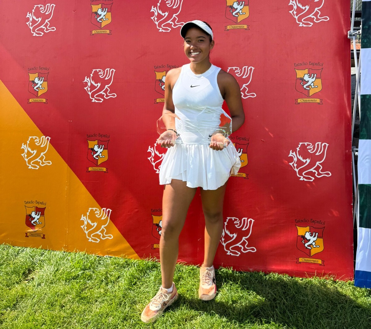 Jovem tenista amazonense, vestindo roupa branca de competição, segura dois troféus após vitória no Torneio ITF 60 em Concepción, Chile.