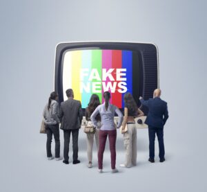 Grupo de pessoas observa uma televisão com a palavra “Fake News” exibida na tela colorida