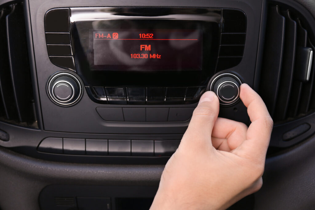 Mão ajustando o dial de rádio no carro, símbolo da resistência do meio na era digital