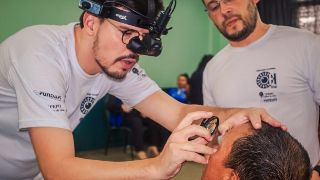 Profissional de saúde examina olho de paciente durante projeto que usa IA para detectar lesões oculares na Amazônia.