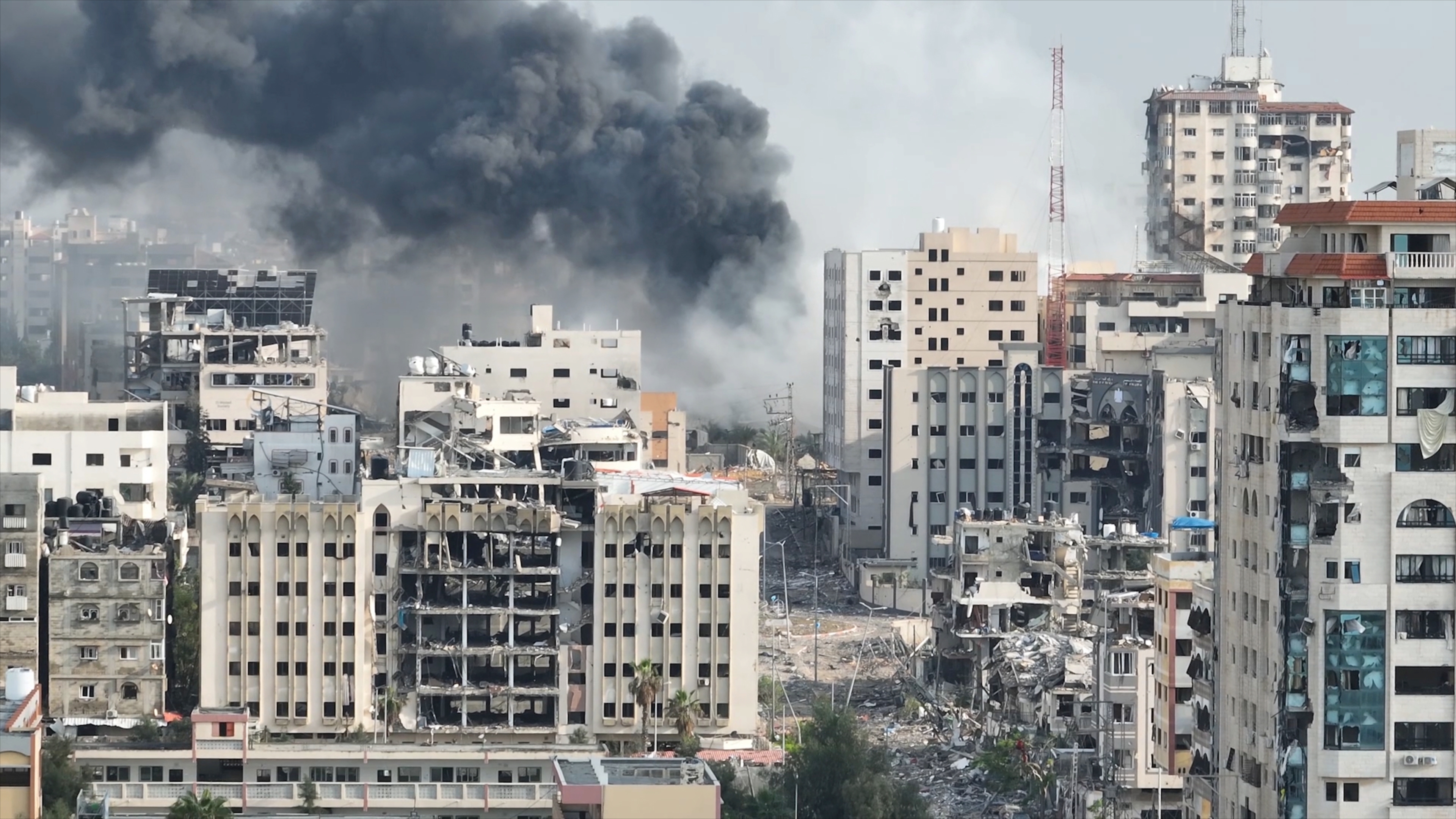 Cidade destruída na Faixa de Gaza com prédios danificados e fumaça após ataques durante o conflito entre Israel e Hamas
