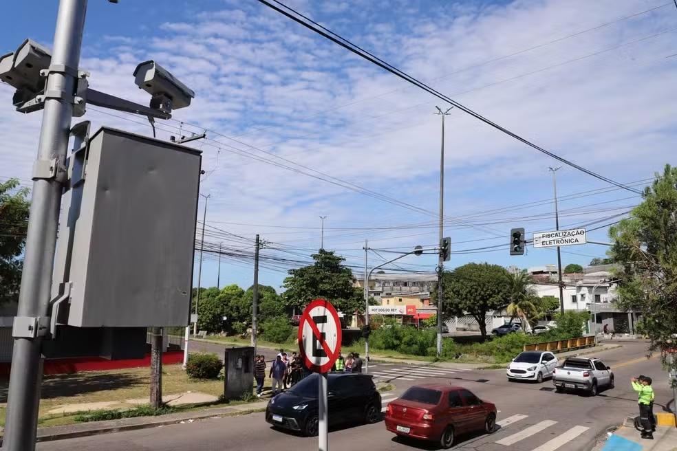 Radares eletrônicos em poste monitoram o trânsito em avenida de Manaus com fluxo de carros e sinalização do IMMU