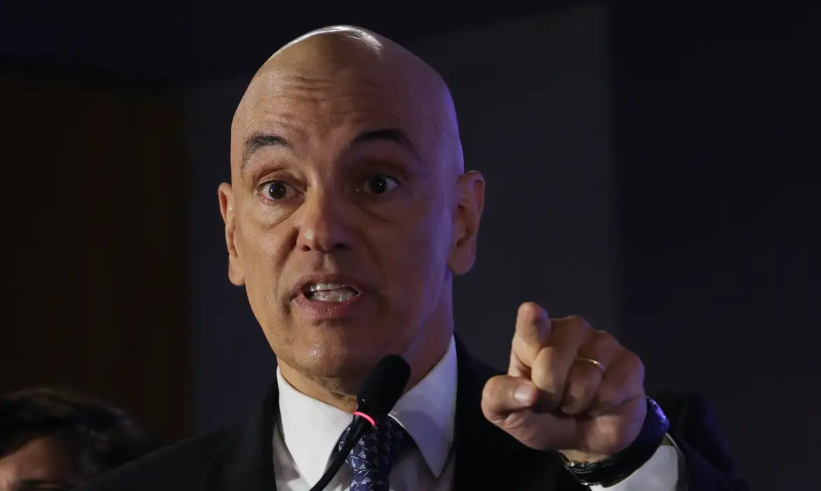 Alexandre de Moraes falando ao microfone e apontando com o dedo, em foto de evento público.
