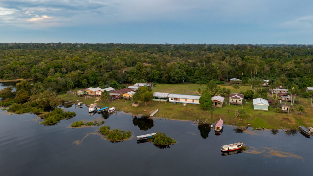 Vista aérea de comunidade ribeirinha na Amazônia cercada por floresta e rio