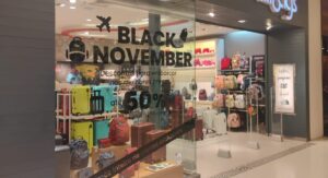 Vitrine de loja em shopping de Manaus com promoções da Black Friday, mostrando malas e mochilas em destaque.