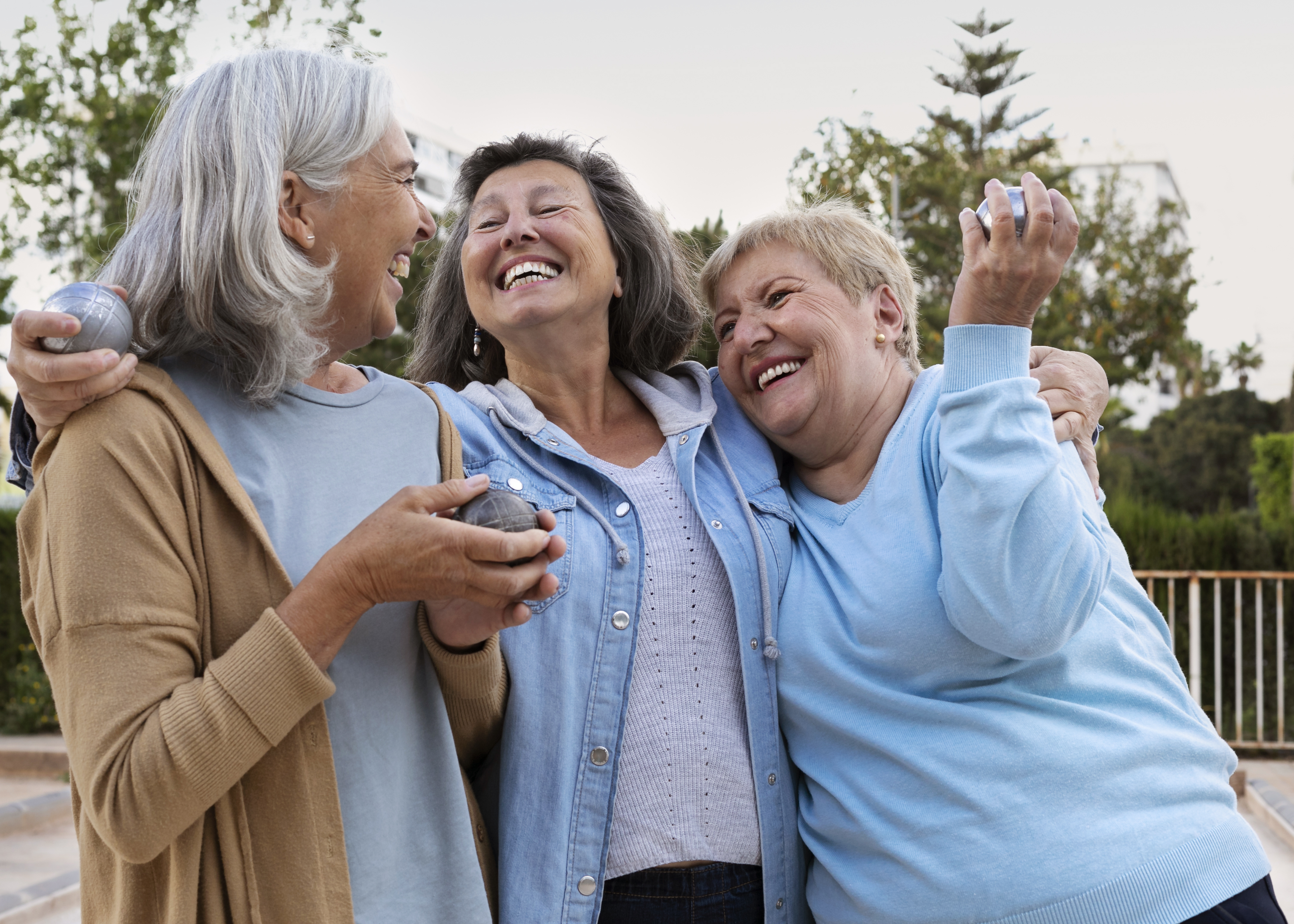 Três mulheres idosas sorrindo ao ar livre, simbolizando o aumento da expectativa de vida no Brasil.