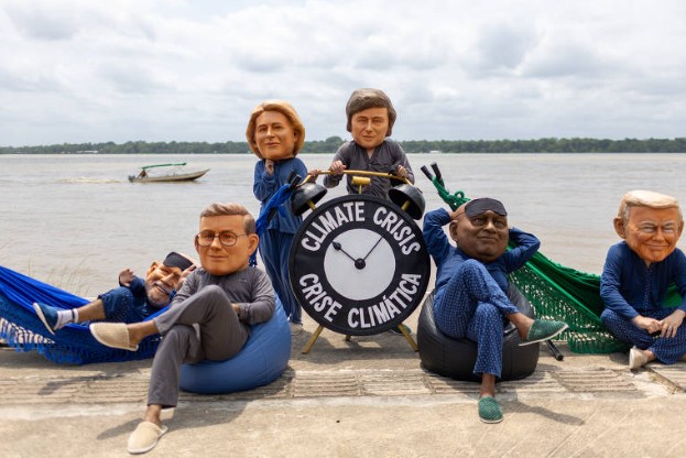 Ativistas caracterizados como líderes mundiais em redes e pufes com relógio escrito “crise climática” em Belém