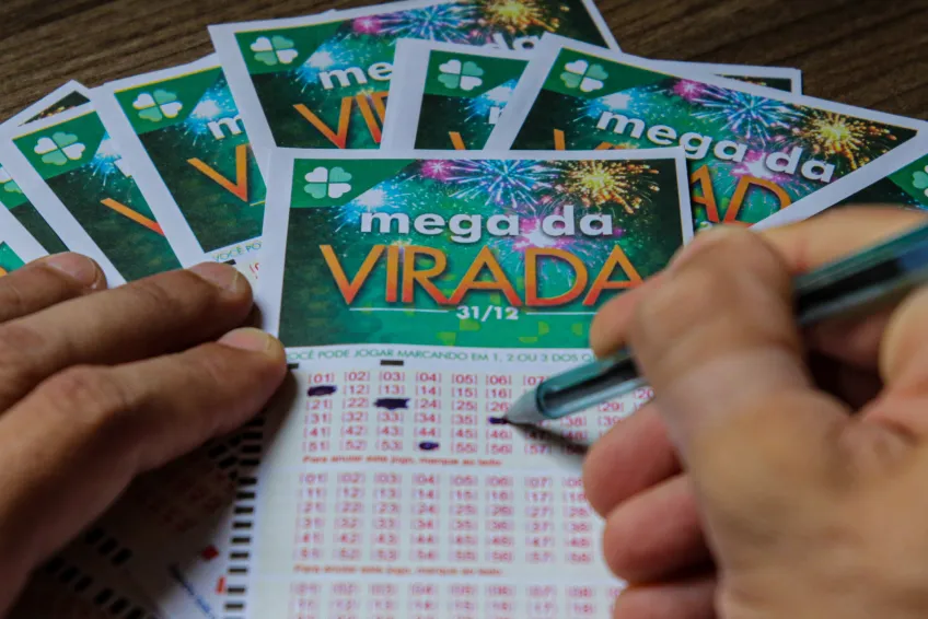 Pessoa marcando números em volantes da Mega da Virada 2025