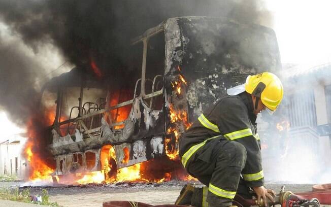 Bombeiro combate incêndio em ônibus queimado durante ação criminosa no Brasil em 2025