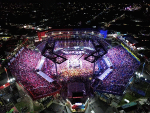 Imagem aérea do Bumbódromo completamente lotado durante o Festival de Parintins à noite.