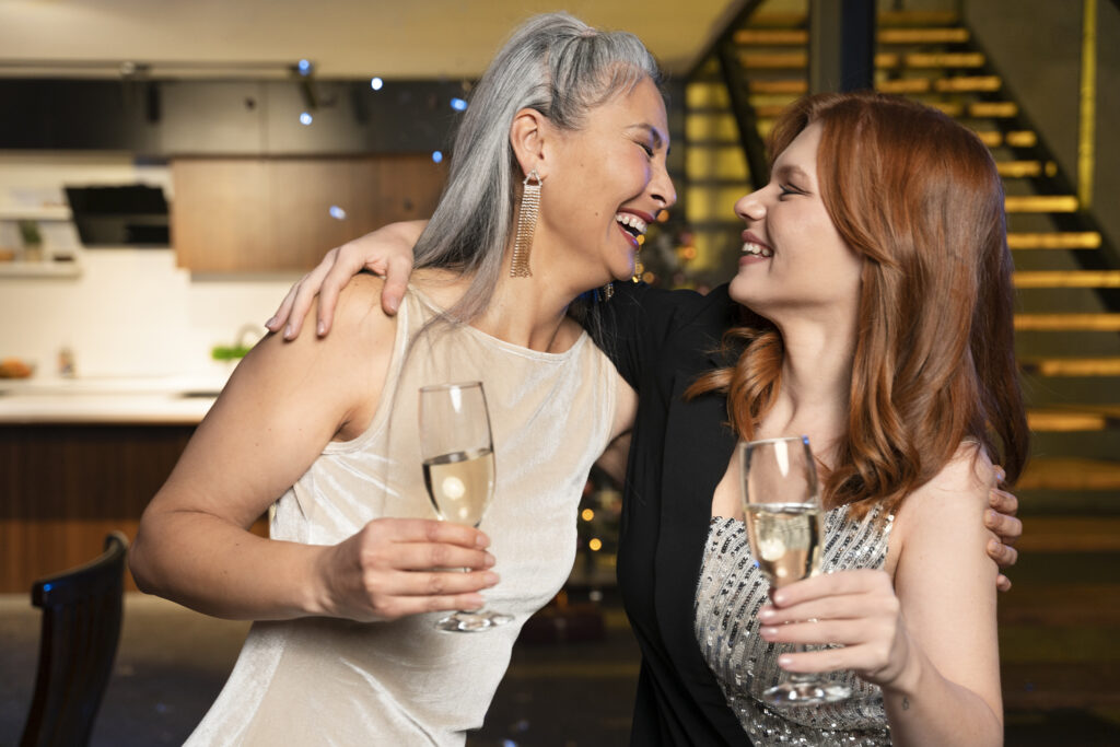 Duas mulheres brindam com taças durante confraternização de fim de ano em ambiente interno