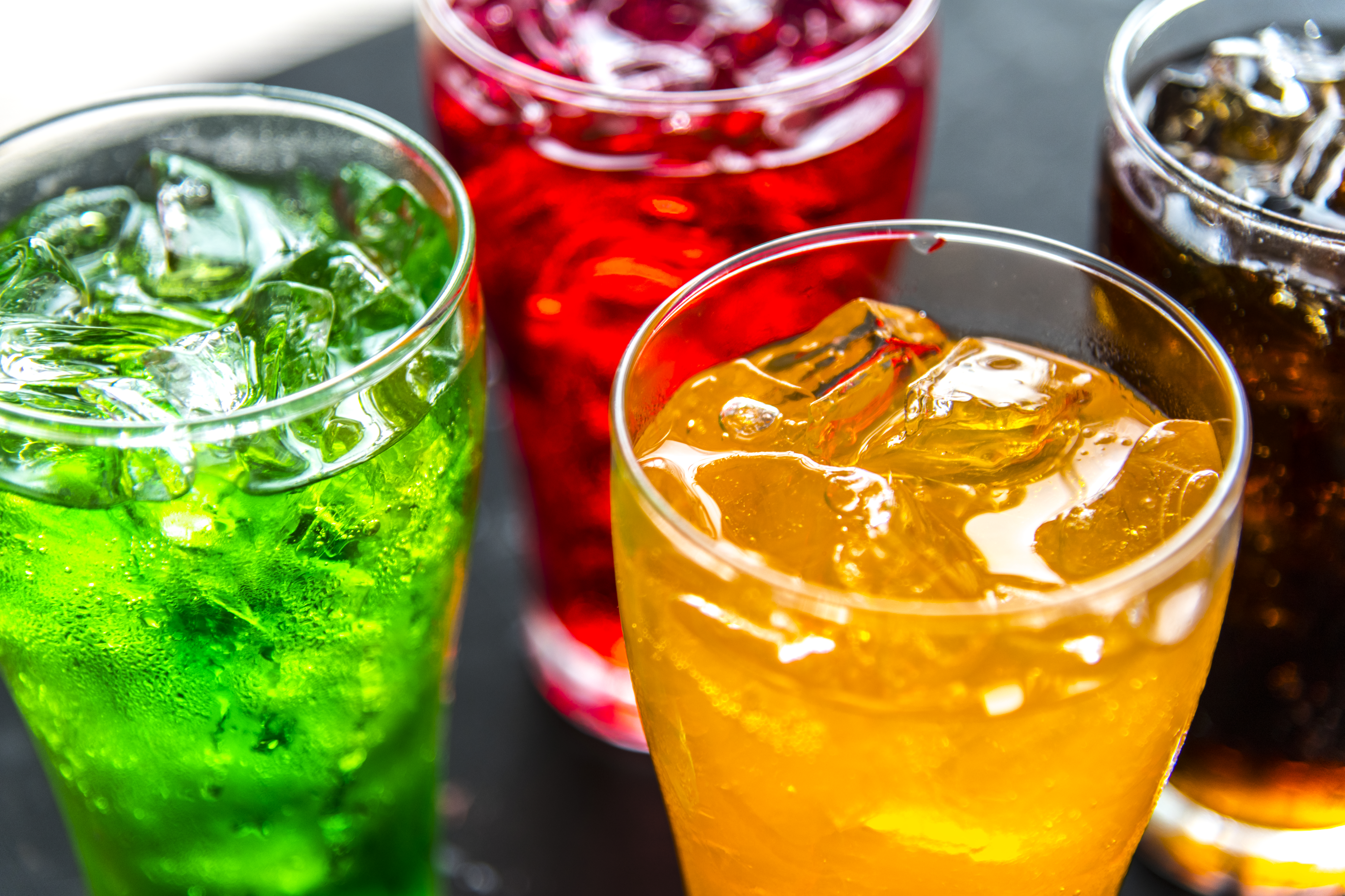 Copos com bebidas coloridas e gelo, como refrigerantes e drinks, que podem piorar a pressão alta.