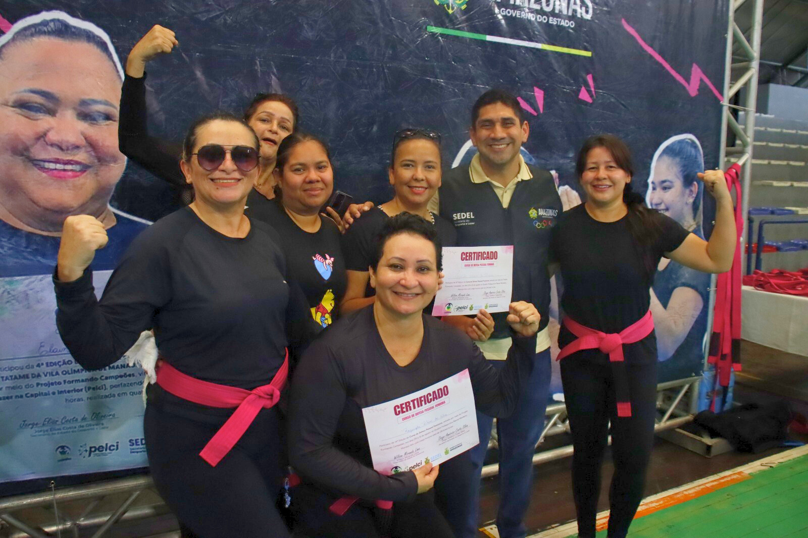 Mulheres participantes do Curso de Defesa Pessoal Feminina seguram certificados em ação realizada pela Sedel, em Manaus.