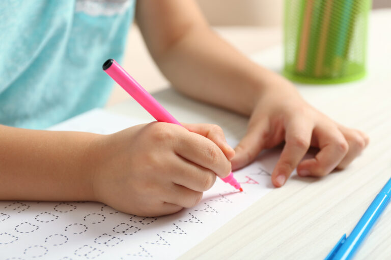 Criança escrevendo em folha de atividades escolares, representando dados do Censo Escolar 2025