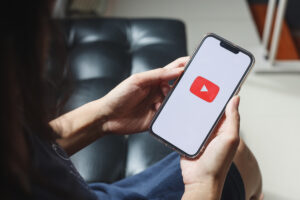 pessoa segurando celular com aplicativo do YouTube aberto