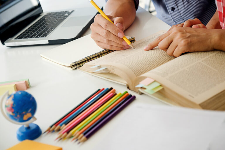 Estudantes consultam livro durante atividade de estudos em sala de aula.