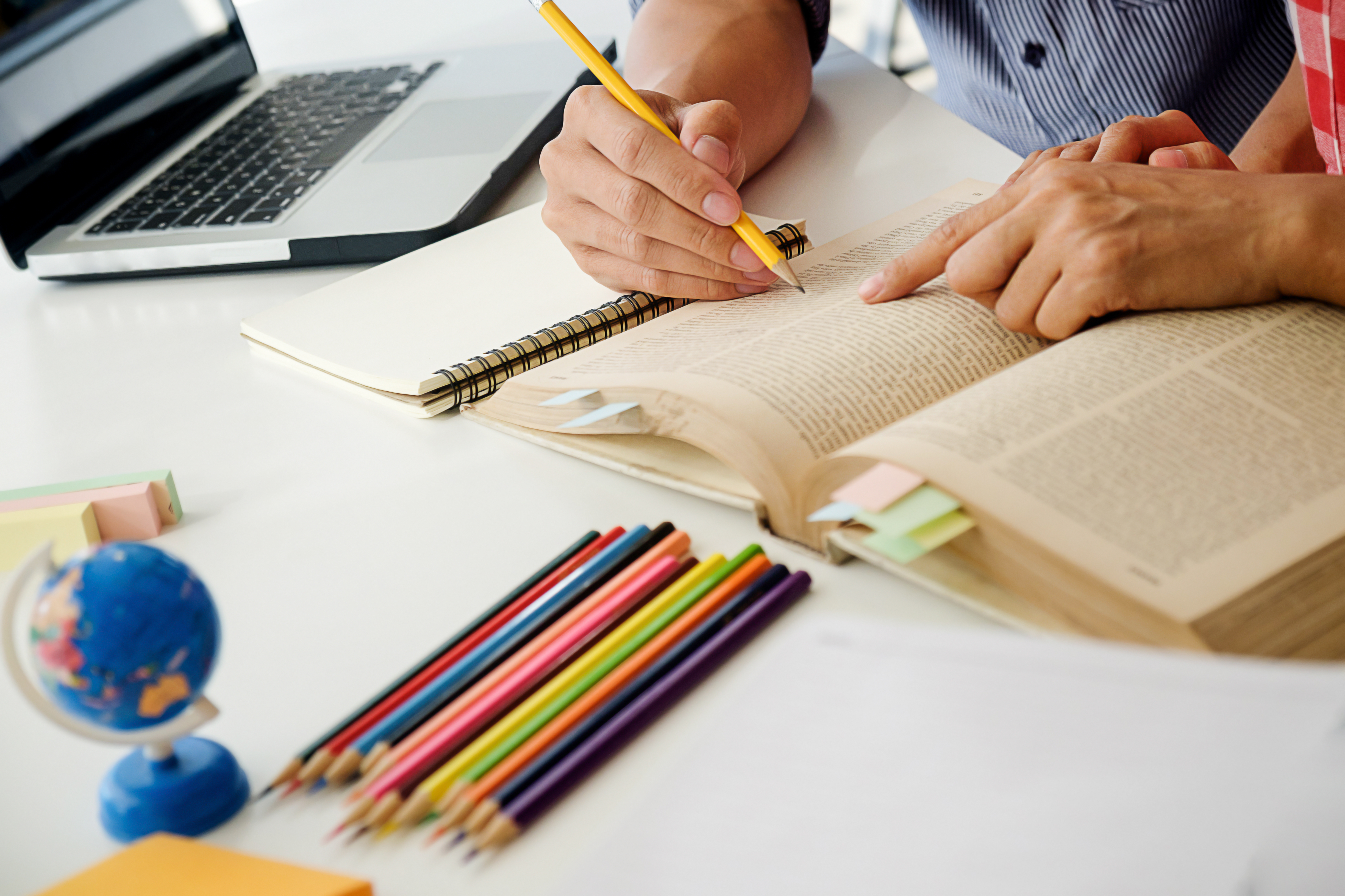 Estudantes consultam livro durante atividade de estudos em sala de aula.