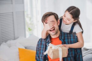 Criança entrega presente ao pai em comemoração ao Dia dos Pais.