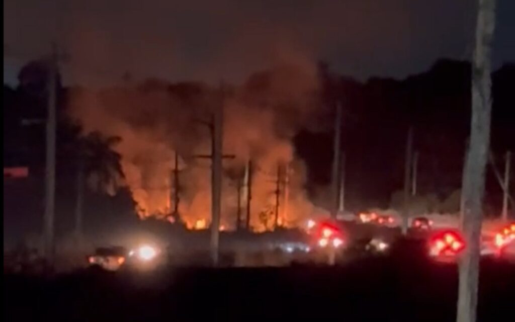 Incêndio em área de vegetação às margens da rodovia AM-010 durante a noite.