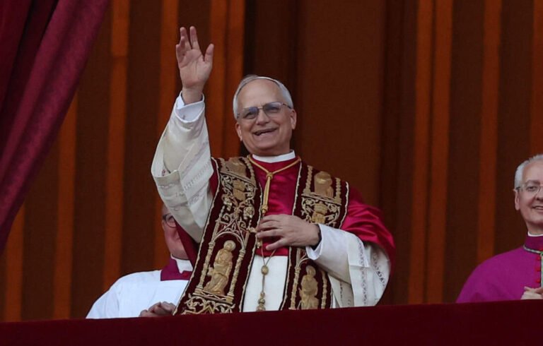 Papa Leão XIV acena de uma sacada, acompanhado por integrantes da Igreja Católica