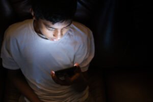 Adolescente utiliza celular em imagem ilustrativa sobre abuso sexual online