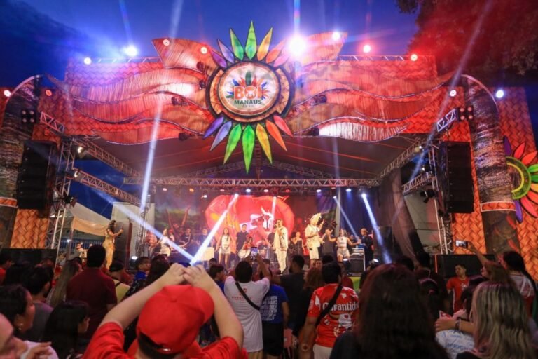 Palco iluminado do Boi Manaus com artistas se apresentando e público acompanhando o espetáculo