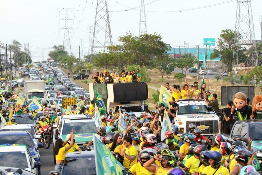 Carreata com carros, motocicletas e apoiadores segurando bandeiras do Brasil durante ato de campanha em Manaus